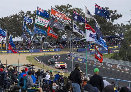 race track with supercars racing and crowd cheering with flags