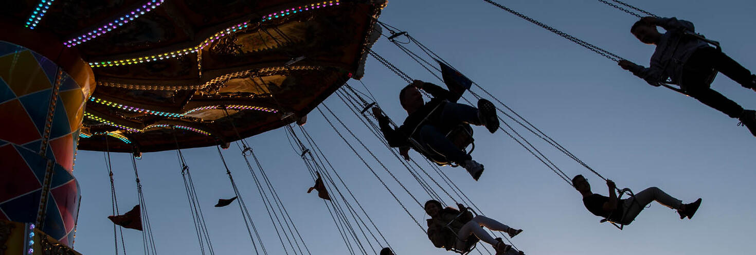 Silhouette of show-goers sitting on an amusement ride